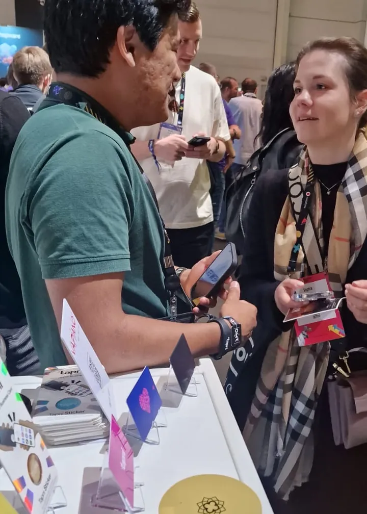 Visitor swapping contact details with a Tapni team member across the booth table
